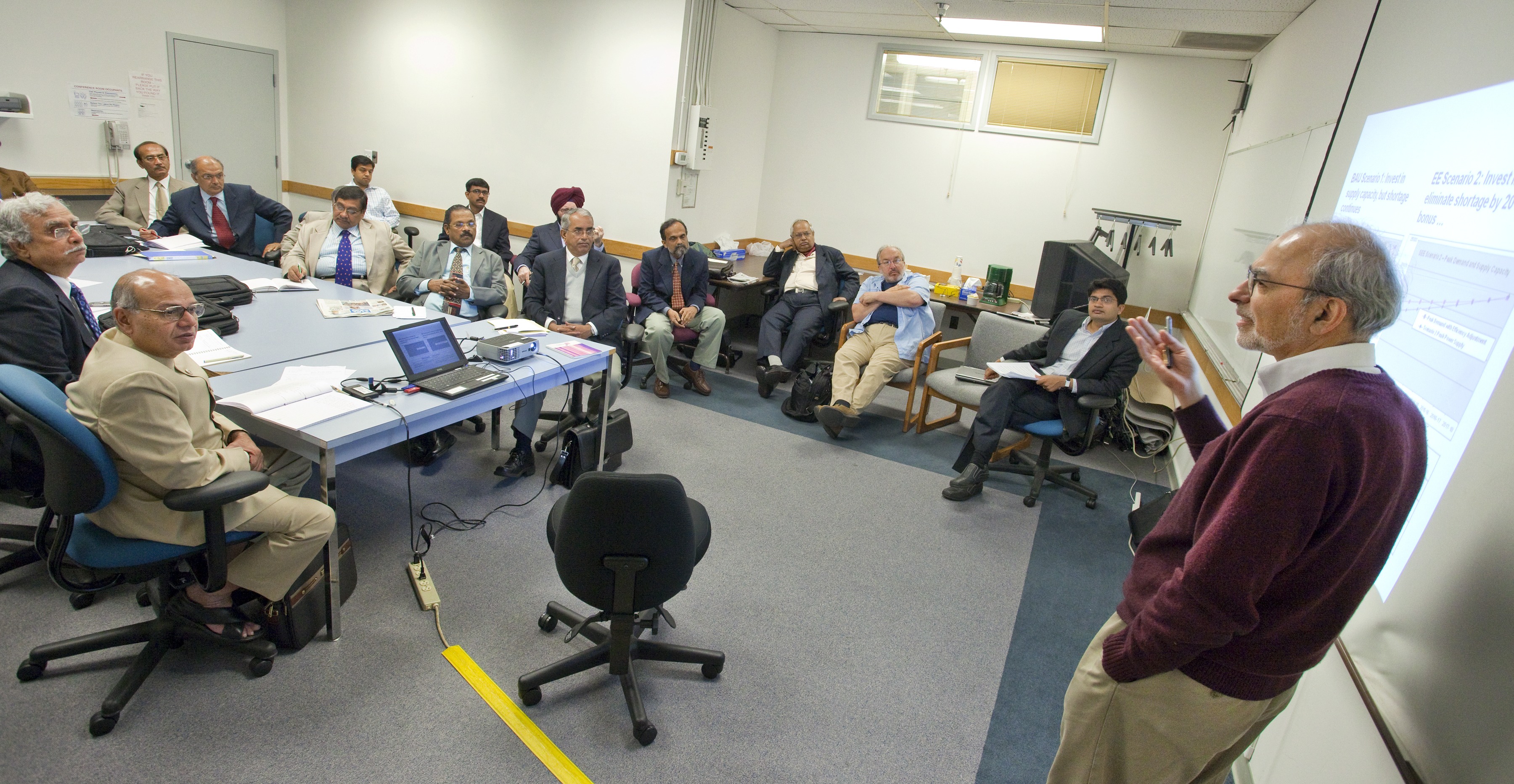 Berkeley Lab scientists Jayant Sathaye (standing) and Amol Phadke (seated, far right) discuss energy efficiency with a visiting group of state electricity regulatory commissioners. Berkeley Lab scientists Jayant Sathaye and Amol Phadke address a group